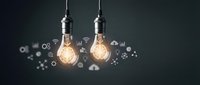 Two glowing vintage light bulbs hanging with technology icons floating around representing innovation, creativity and digital transformation concepts.