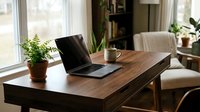 Cozy home office with wooden desk, open laptop, coffee mug, and green plant by bright window, creating productive workspace.