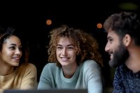 Diverse group of young friends laughing and enjoying time together at night, sharing genuine moments of joy and connection in casual setting.