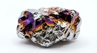 Raw chalcopyrite mineral specimen with iridescent purple and gold metallic surface displaying natural peacock colors on white background.