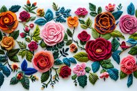 Colorful felt roses and leaves arrangement on white background, featuring pink, orange, burgundy blooms with teal foliage and decorative bumblebees, handmade craft.
