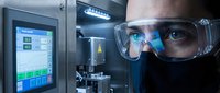 Scientist in protective goggles working with advanced laboratory equipment and digital interface for pharmaceutical research and development.