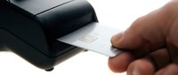 Hand inserting white credit card into black payment terminal for transaction processing and financial services.