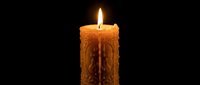 Ornate carved candle with intricate patterns burning bright flame against dark background for meditation, relaxation, spa treatments and spiritual practices.