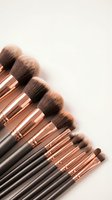 Professional makeup brush set with rose gold ferrules and black handles arranged on neutral background for beauty and cosmetics applications.
