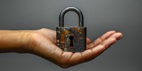Rusty vintage padlock held in open palm against gray background, symbolizing security, protection, and privacy concepts for business and technology presentations.