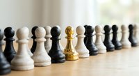Golden chess pawn standing out among black and white pawns on wooden board, symbolizing leadership, uniqueness and strategic thinking in business.