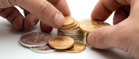Hands of a Caucasian adult stacking gold and silver coins on a white surface, symbolizing savings, investment, and financial wealth management.