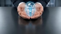 Businessman hands protecting glowing digital human head with geometric patterns representing artificial intelligence and technology innovation.