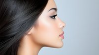 Side profile of young Asian woman with flawless skin, long black straight hair, and natural makeup against light gray background. Professional beauty portrait.