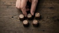Hand selecting wooden dice with legal scales and paragraph symbols on rustic wood surface for law firm branding and justice concept materials.