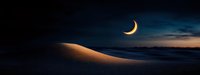Crescent moon illuminating sandy dunes at twilight, dramatic panoramic desert landscape with dark blue sky and glowing horizon creates mystical atmosphere.