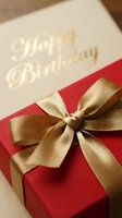 Red gift box with elegant gold satin bow beside a Happy Birthday card, capturing the joy of celebration and gifting.