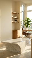 Modern minimalist living room interior with curved marble coffee table, built-in wooden shelving, natural lighting and contemporary furniture design.