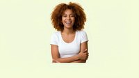 Young African American woman with curly auburn hair laughing with arms crossed, wearing white t-shirt, isolated on light green background.