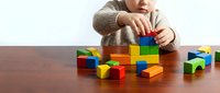 Young child playing with colorful wooden building blocks on a table, stacking and constructing, developing motor skills and creativity.