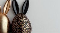 Decorative Easter eggs with bunny ears in metallic gold and animal print pattern on neutral background, modern festive holiday decor arrangement.