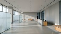 Modern minimalist office lobby with polished concrete flooring, floor-to-ceiling windows, and contemporary furniture for corporate workspace design.