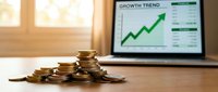 Stacked gold coins with growth trend chart on laptop screen, representing financial success, investment returns, and business profit growth.