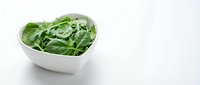 Fresh green leafy salad in white heart-shaped bowl on white background, suitable for healthy eating, nutrition, diet, and food photography projects.
