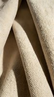 Beige linen fabric with natural texture and soft folds, showcasing woven material details for fashion, interior design, and textile projects.