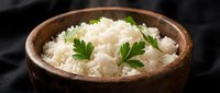 Steamed white rice garnished with fresh parsley in rustic wooden bowl on dark background for healthy meal preparation and cooking concepts.