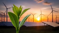 Green plant sprout growing with wind turbines and solar panels at sunset representing sustainable renewable energy and environmental growth.