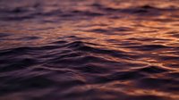 Ocean waves at sunset with dramatic purple and orange sky reflection on water surface creating peaceful seascape for meditation and relaxation concepts.