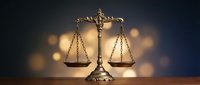 Golden scales of justice on dark background with warm bokeh lights symbolizing legal system fairness and judicial balance for law firm branding.