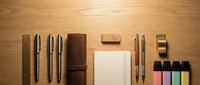 Professional workspace flat lay with leather notebook, pens, sticky notes and office supplies arranged on wooden desk background for branding mockup.