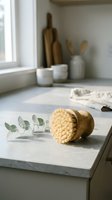 Natural wooden dish brush with eucalyptus branch on marble kitchen counter in bright minimalist interior for eco-friendly cleaning and sustainable living.