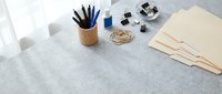 Modern minimalist workspace with stationery supplies, wooden pencil holder, kraft paper envelopes and office accessories on marble surface for productivity.