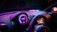 Neon glowing speedometer gauge on modern car dashboard with purple and blue lighting effects, automotive interior detail with digital display technology.