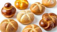 Assorted fresh baked bread rolls and buns with sesame seeds on white background, isolated bakery products for food design and culinary projects.