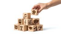 Hand placing wooden cube with dollar sign on pyramid of blocks featuring creative arts symbols isolated on white background for educational design.