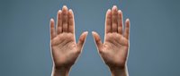 Two open hands raised up showing palms in stop gesture or surrender pose against blue background for communication and body language concepts.