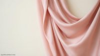 Soft pink silk fabric with elegant draping folds against neutral background, luxury textile material for fashion design and interior decoration projects.