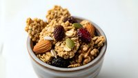 Homemade granola with nuts, dried fruits and seeds in ceramic bowl. Healthy breakfast cereal mix with almonds, walnuts, cranberries and pumpkin seeds.