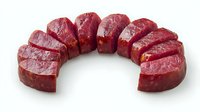 Fresh raw beef tenderloin sliced into portions arranged in curved line on white background, premium cut meat ready for cooking, isolated food photography.