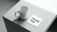 White ceramic mug beside a Thank You note card on a concrete surface, monochrome minimalist style for gratitude and appreciation concepts.