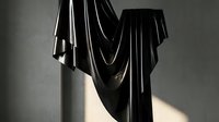 Dramatic black fabric draped elegantly with soft lighting creating shadows and highlights for fashion design projects and artistic compositions.