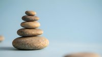 Zen stone stack balanced on smooth surface with soft blue background for meditation wellness spa and mindfulness concepts.