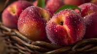 Fresh ripe peaches with water droplets in wicker basket, organic summer stone fruit harvest for healthy eating and cooking recipes.