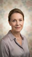 Professional mature Caucasian businesswoman in gray blouse smiling confidently at camera. Corporate headshot for business profiles and marketing materials.