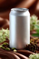 Blank aluminum beverage can mockup with condensation drops surrounded by pistachio nuts and chocolate swirls on brown background for product packaging design.
