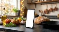 Smartphone with blank white screen mockup on kitchen counter surrounded by fresh vegetables, bread, and cooking ingredients for recipe apps.