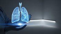 Glowing blue lungs hologram floating above open palm in dark medical environment. Healthcare technology concept for respiratory system education and treatment.