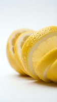 Fresh sliced lemon rounds arranged in a row on white background, showcasing vibrant yellow citrus texture and juicy pulp in macro detail.