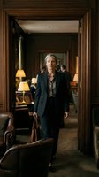Confident senior businesswoman in elegant suit standing in luxury office doorway with briefcase, professional corporate executive portrait.