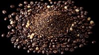 Fresh roasted coffee beans and ground coffee powder arranged in artistic composition on dark background, creating contrast between whole beans and fine grounds.